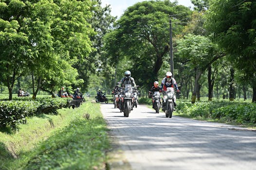 A group of motorcyclists enjoying a ride through a green pathway in Guwahati, India.