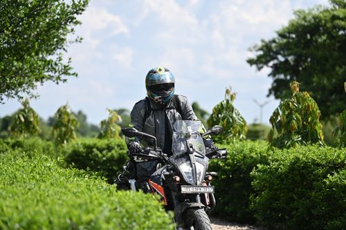 Free A person riding a motorcycle through lush greenery in Guwahati, India, enjoying a sunny day. Stock Photo