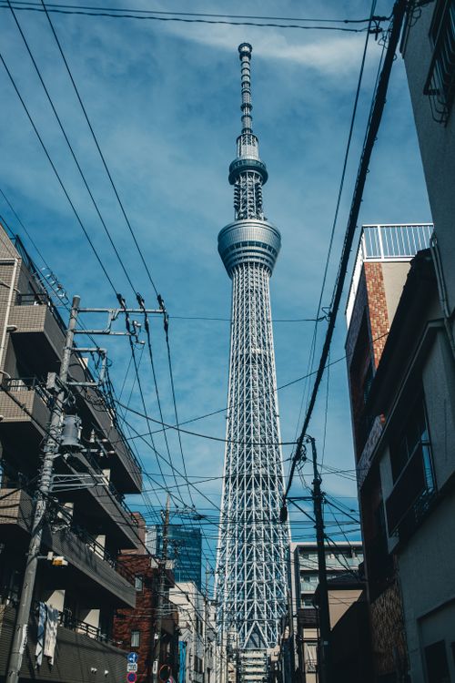 Free View of the iconic Tokyo Skytree amidst urban residential buildings under a clear blue sky. Stock Photo