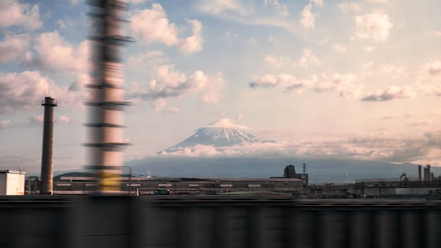 Mount Fuji viewed from behind a blurred industrial scene, blending nature with urban elements.