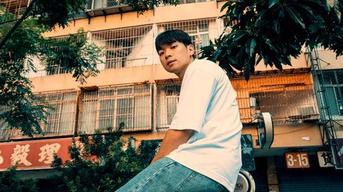 Free Asian man sitting on a scooter in front of urban building during daytime. Stock Photo