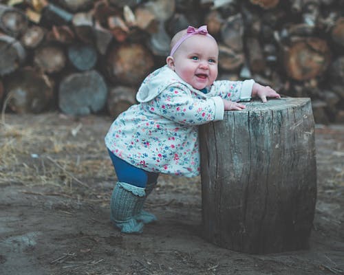 Free Toddler Standing and Leaning Against Log Stock Photo