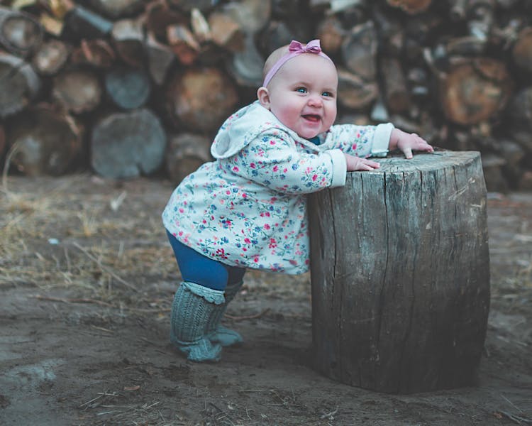 Toddler Standing And Leaning Against Log