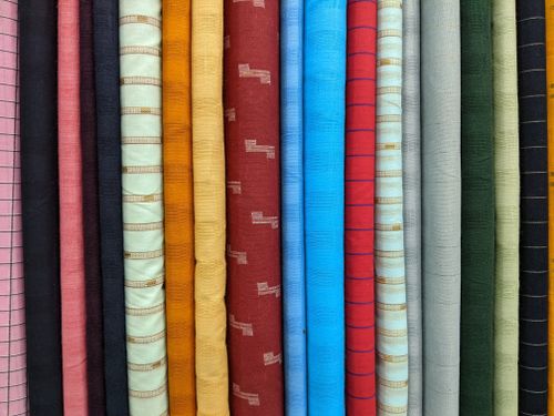 Free A vibrant selection of fabric rolls in various colors and patterns displayed in a vertical stack. Stock Photo