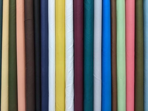 Free A close-up view of colorful rolled fabrics showcasing a variety of hues and textures. Stock Photo