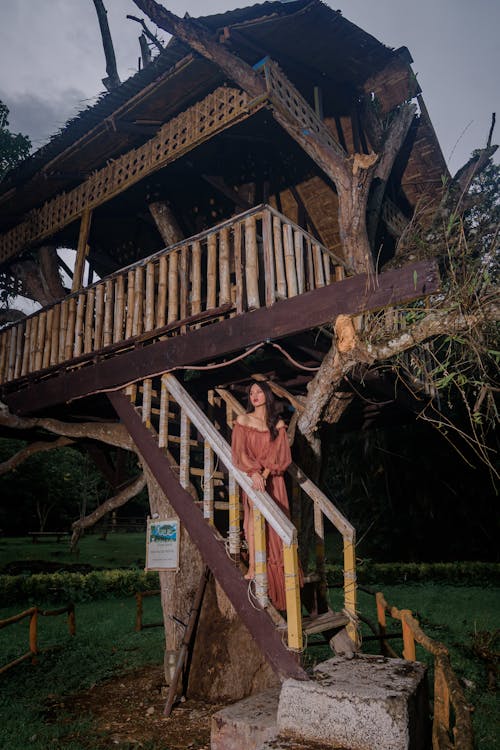 Woman in Dress Posing on Stairs of House behind Tree