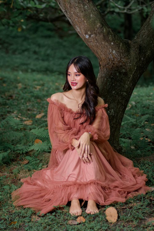 Woman in Dress Sitting and Posing by Tree