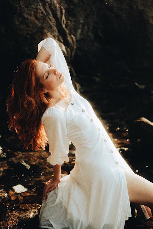 Woman in Buttoned Sun Dress Bending on Rock · Free Stock Photo