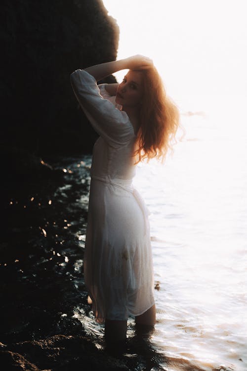Woman in White Sun Dress Standing in Shallow Sea
