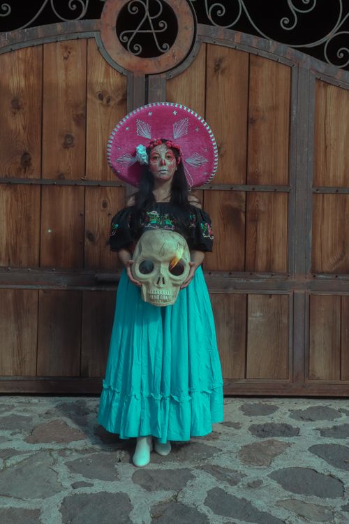 Free Traditional Catrina costume for Día de Muertos in Mexico City holding a skull. Stock Photo