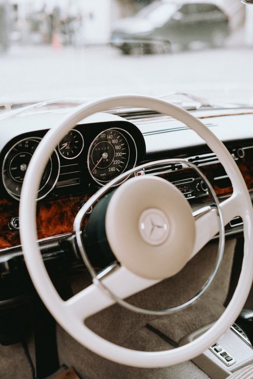 Free Close-up of a classic car dashboard featuring a vintage steering wheel and speedometer. Stock Photo