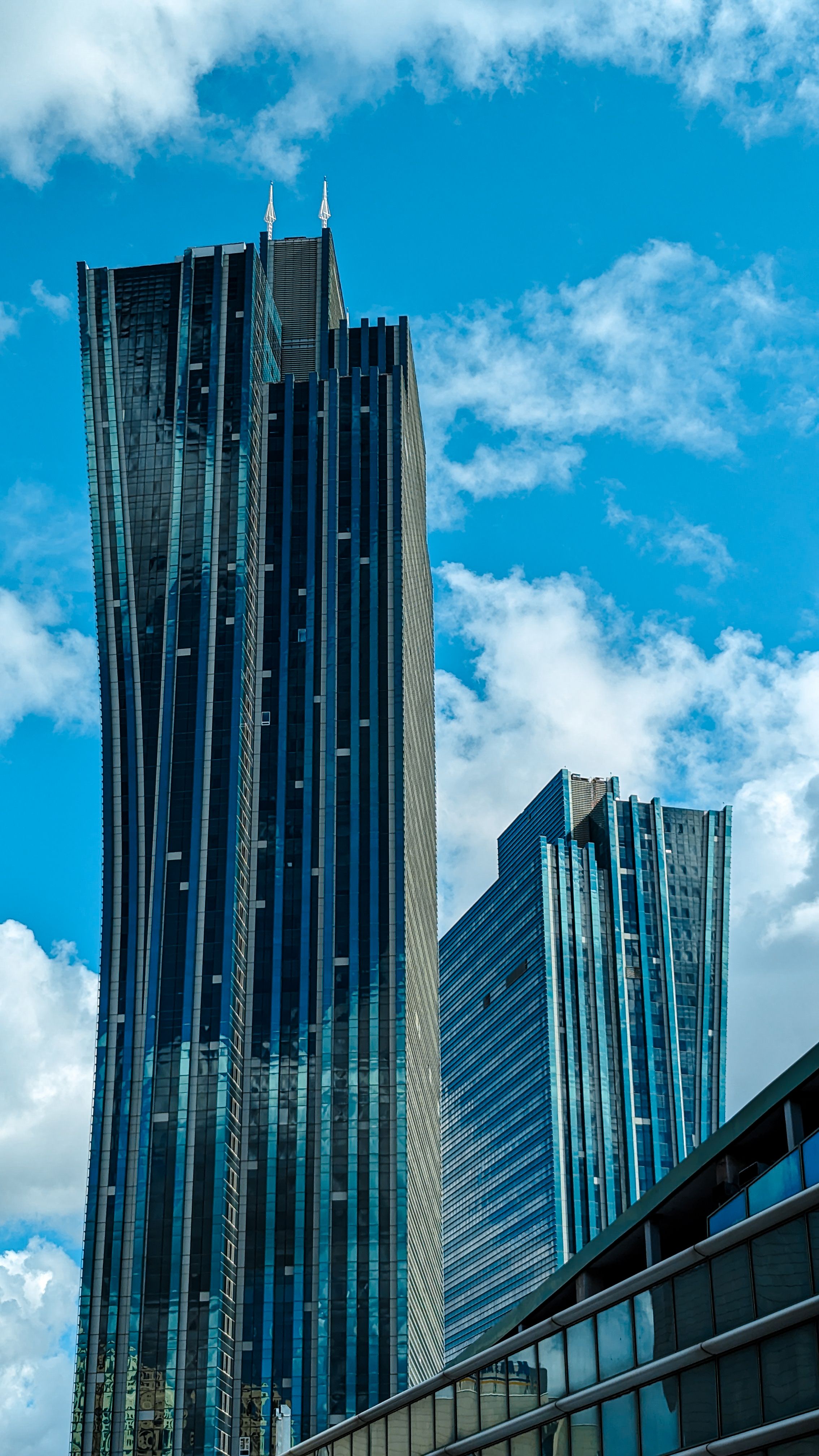 Tall modern skyscrapers in Astana, Kazakhstan, reaching into a clear blue sky with white clouds.