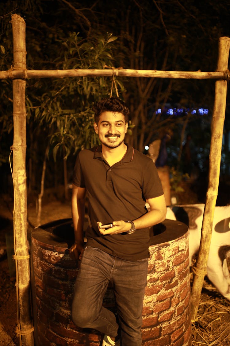 Smiling Man Standing By Well At Night