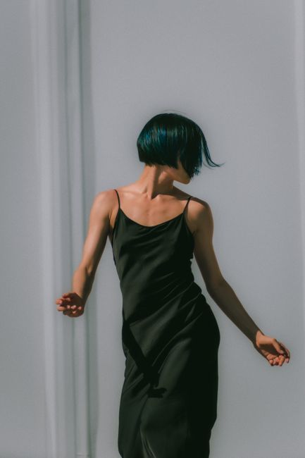 Stylish woman in a black silk dress with a chic hairstyle, exuding elegance.