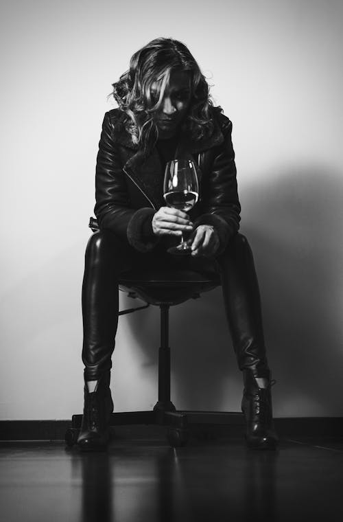 Woman in Black Leather Clothing Sitting with Wineglass in Hand