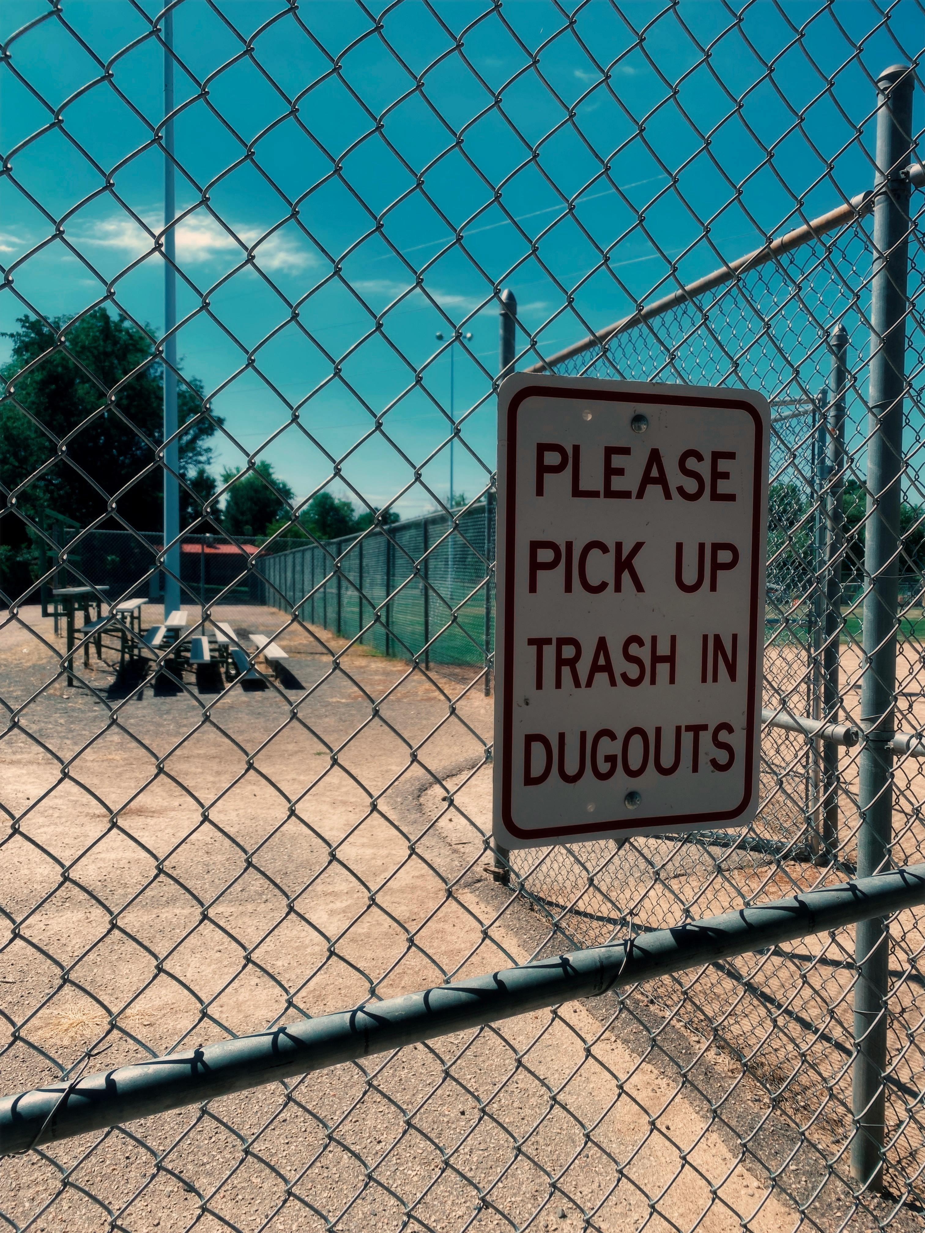 close up of a sign hanging on the fence surrounding a baseball field