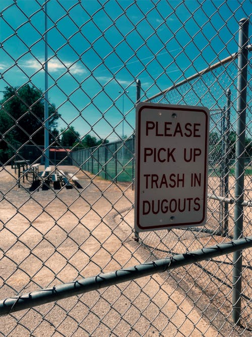 Close-up of a Sign Hanging on the Fence Surrounding a Baseball Field 