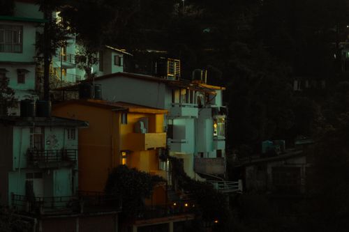 Free A serene urban landscape during twilight, showcasing illuminated houses against a dark backdrop. Stock Photo