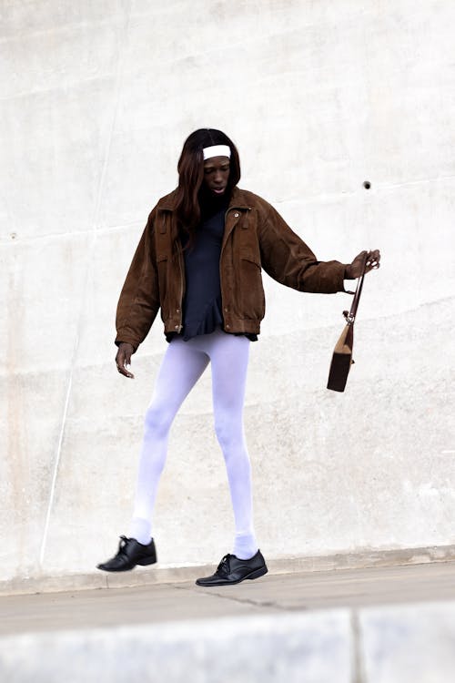 A Model in a Fashionable Outfit Posing on a Sidewalk by a Wall of a Building in City 