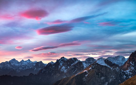 Captivating sunset over the snow-covered peaks of the Dolomites, with vivid pink and blue skies.