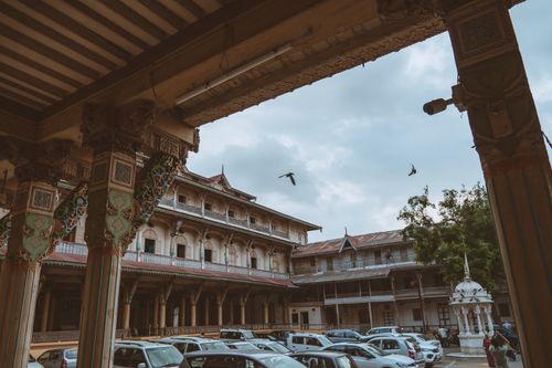 Free View of a historic courtyard featuring traditional architecture with ornamented columns and parked cars. Stock Photo