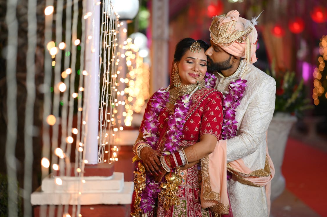 Smiling and Kissing Newlyweds in Traditional Clothing with Garlands