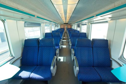 An empty modern train interior with blue seats, offering a comfortable travel space.