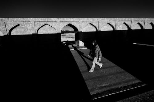 Woman Walking near Ancient Building Wall