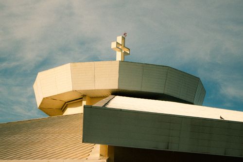 Free Contemporary church rooftop with a prominent cross against a blue sky in São Paulo, Brazil. Stock Photo
