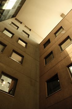 Urban building facade with modern design and reflections captured in a courtyard view.
