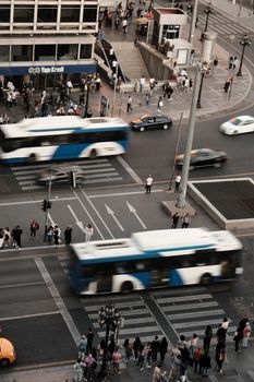 Aerial view of busy city streets with buses and pedestrians at a crosswalk.