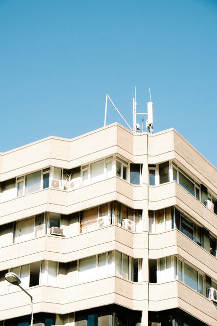 Low angle view of a contemporary residential building with antennas against a blue sky.