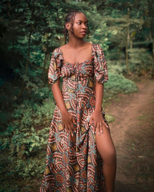Free Elegant portrait of a woman standing on a forest path in a patterned dress. Stock Photo