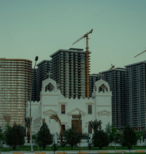 Free Photo of construction cranes over modern buildings with a historic church in Erbil, Iraq. Stock Photo