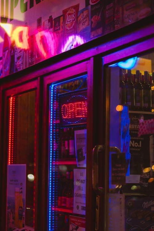 Free Vibrant neon lights illuminate a convenience store entrance during nighttime in an urban setting. Stock Photo