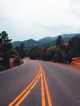 Winding road through a lush forest with mountains in the distance, perfect for travel themes.