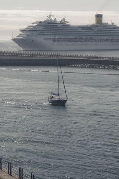 A cruise ship and sailboat navigate peaceful coastal waters, showcasing maritime elegance.