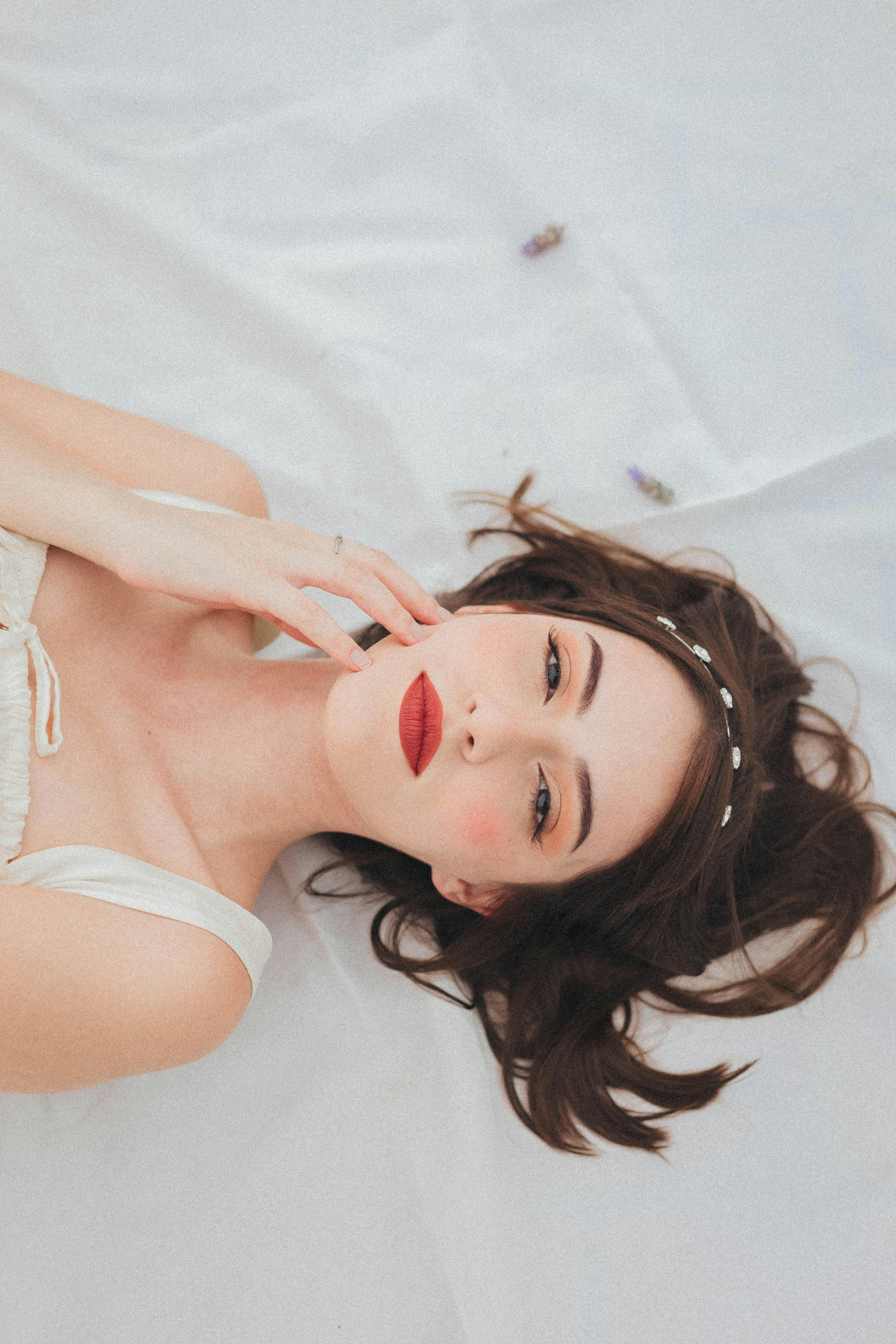 Portrait of a woman with red lips lying on a white background.