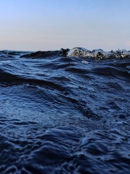 Dynamic close-up of ocean waves with a visible horizon at twilight.