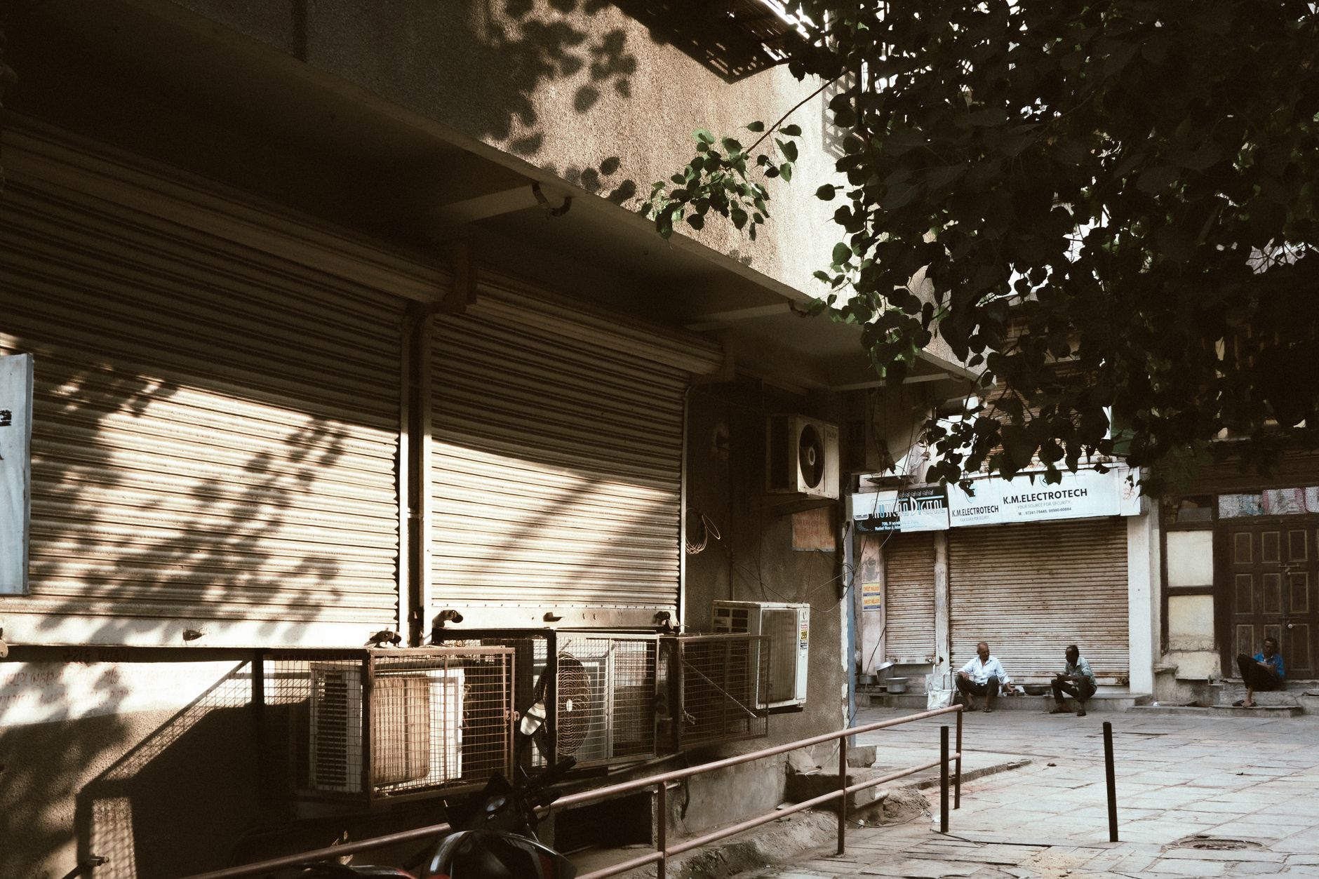 Shuttered shopfronts on a quiet Cypriot street during afternoon siesta