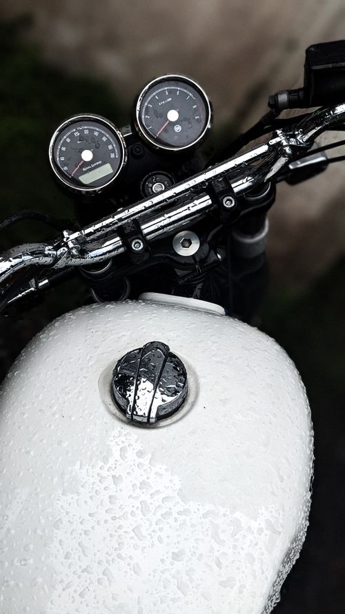 Free Detailed close-up of a motorcycle handlebar and speedometer, covered in raindrops, emphasizing texture and detail. Stock Photo