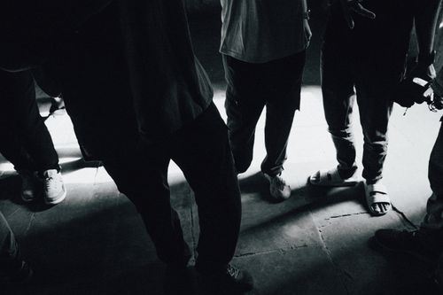 Free Group of people standing on a sunlit concrete pavement, showing shadows and footwear. Stock Photo