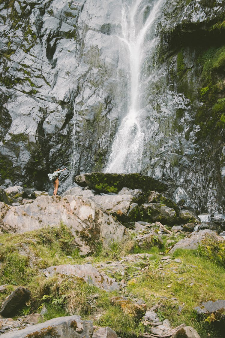 Woman Near Waterfall On Rocks