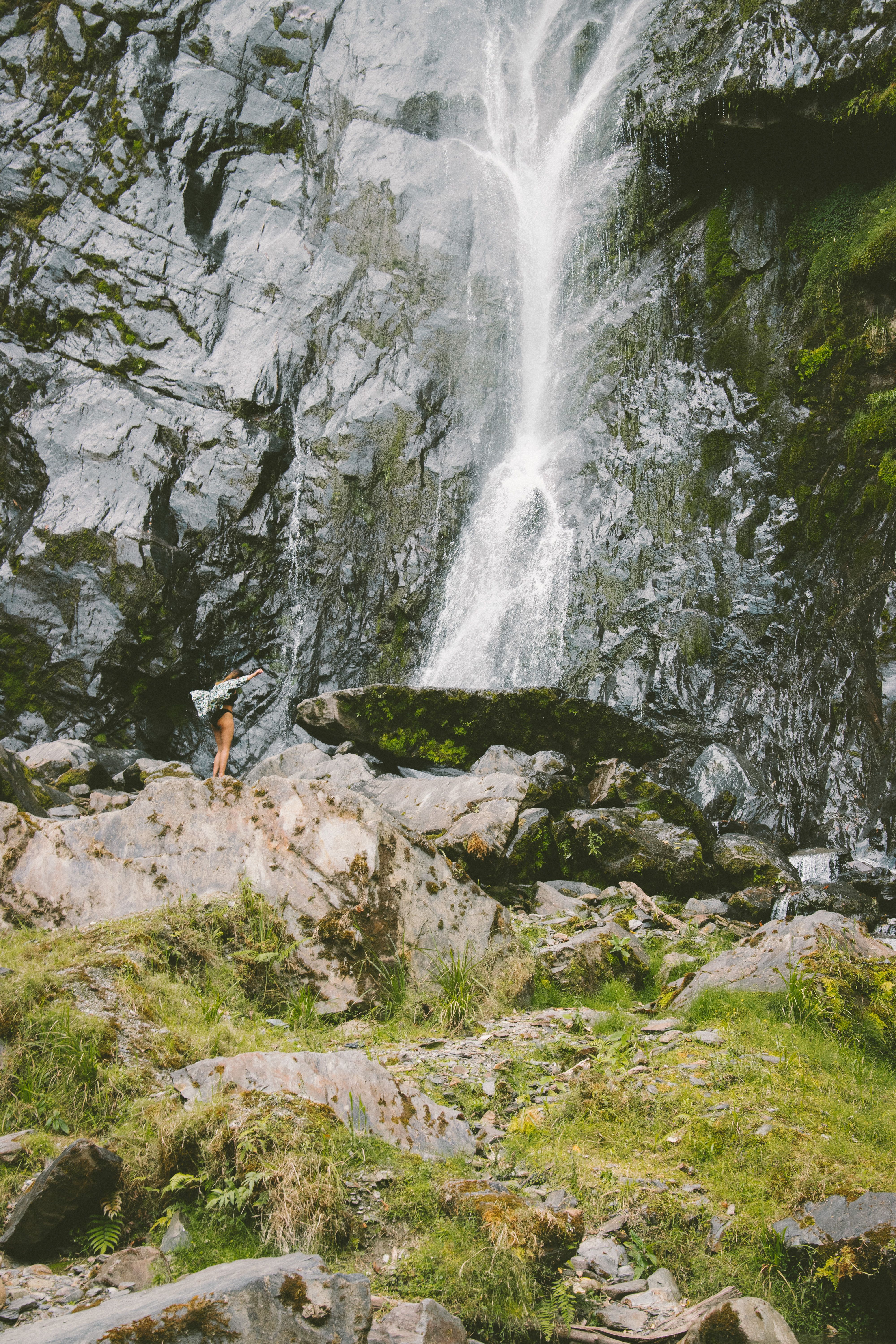 Woman near Waterfall on Rocks · Free Stock Photo