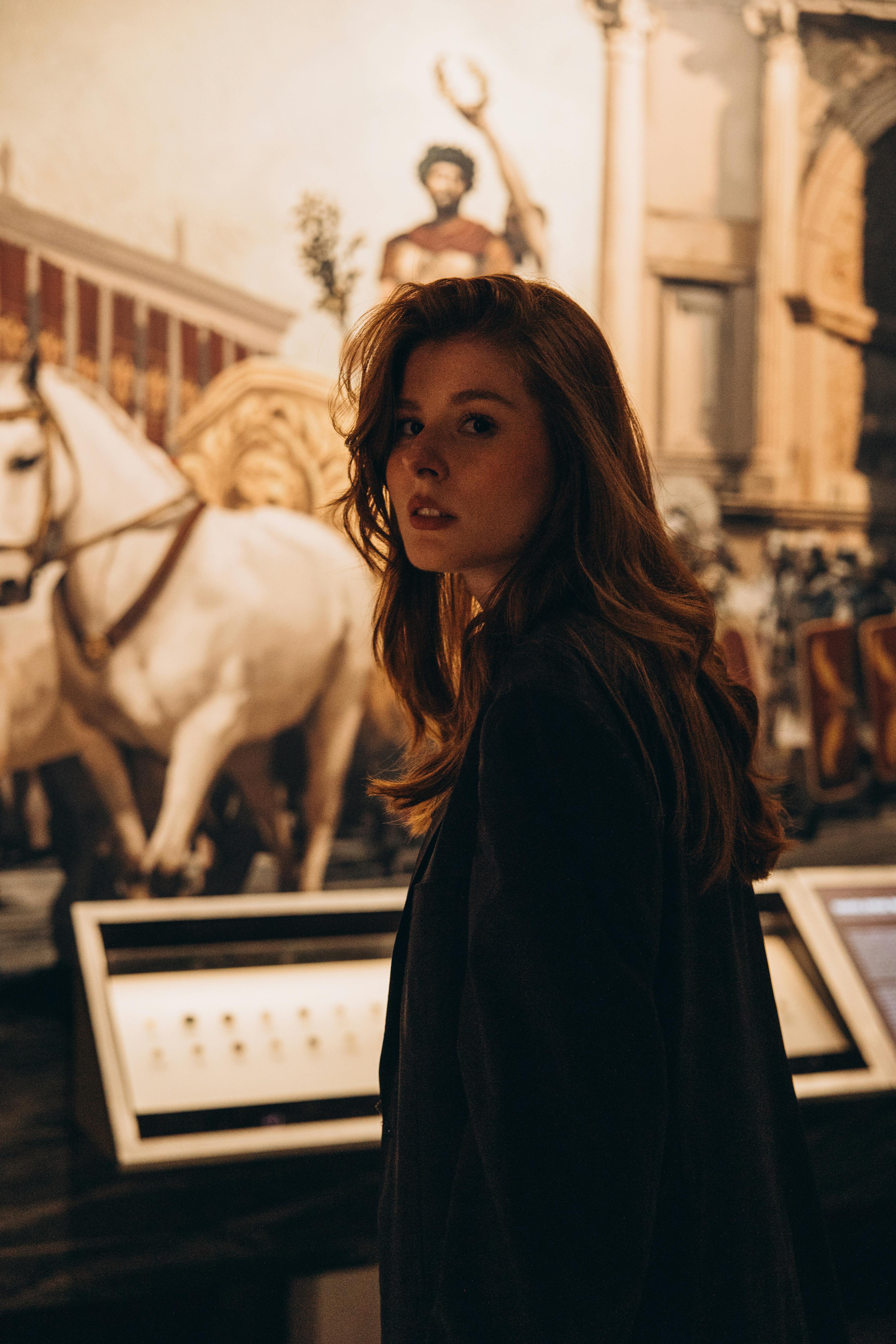 a woman standing in front of a museum with a painting