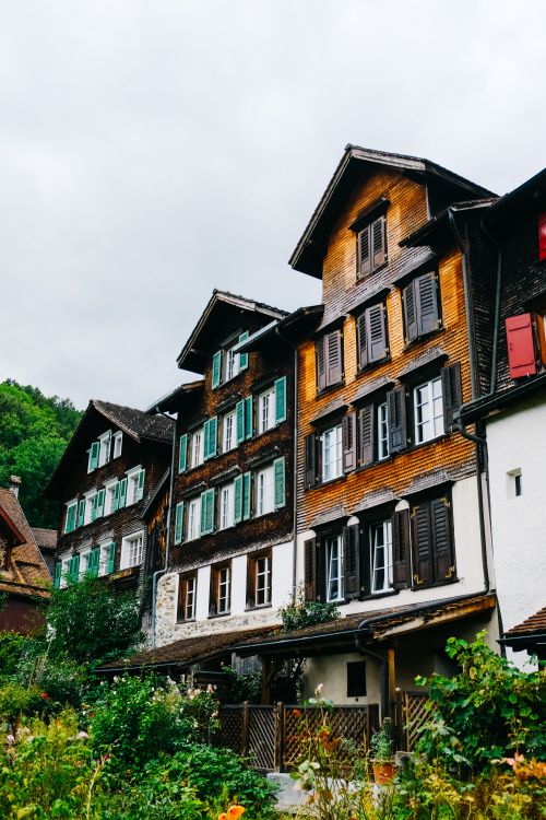 Free Picturesque European townhouses with colorful shutters and wooden facades set against cloudy skies. Stock Photo