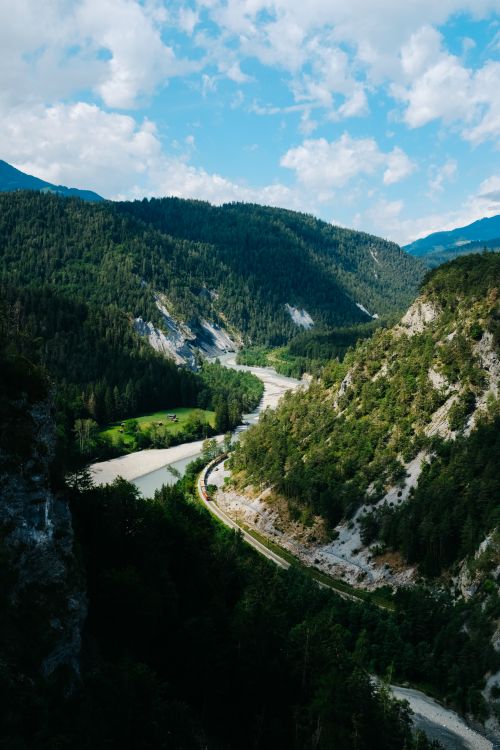 Free A breathtaking aerial view of mountains, forest, and a winding river under a blue sky. Stock Photo