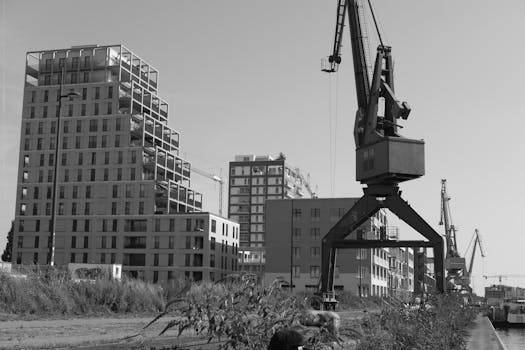 Black and white photo of urban construction showing cranes and modern buildings.