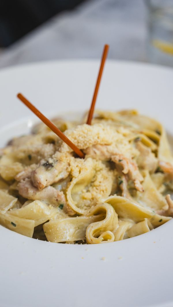 Creamy pasta with chicken and parmesan in a white bowl — photo by Yusuf Kaya on Pexels