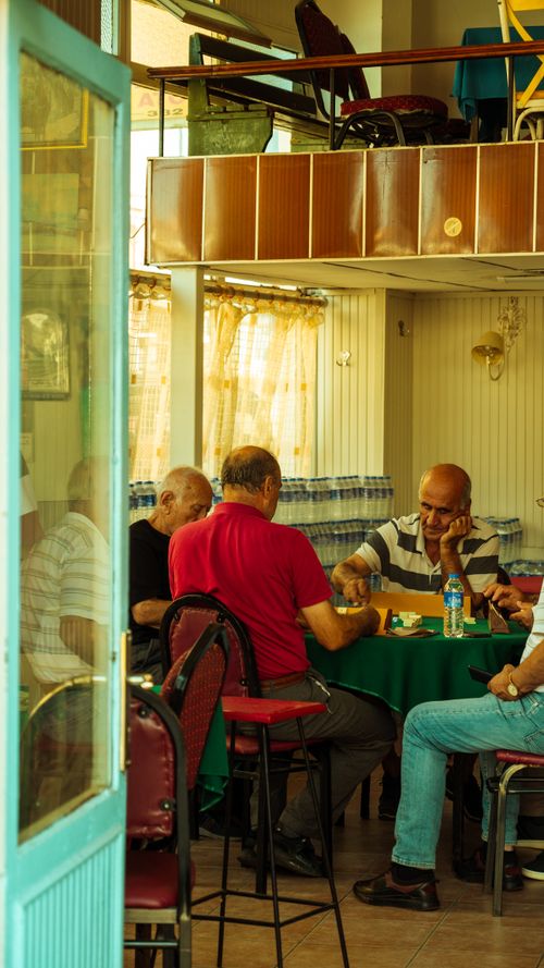 Free Four mature men sitting at a café table playing games and enjoying leisure time indoors. Stock Photo